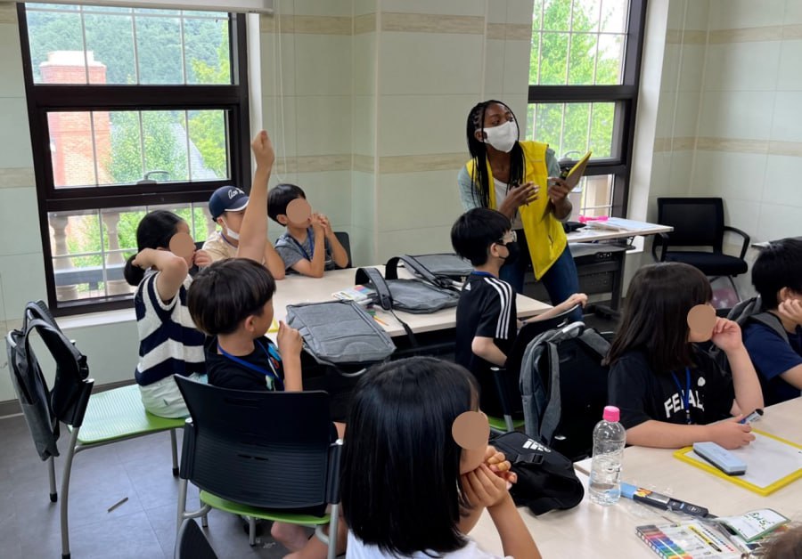 교실에서 원어민 교사와 학생들이 수업하고 있는 모습. 손을 들며 적극적으로 수업에 참여하고 있는 모습을 볼 수 있다.